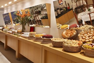 A buffet table with various food items and a vase of flowers.