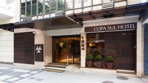 The exterior of the Copa Sul Hotel, featuring a modern facade, large entrance doors, and potted plants at the entrance. - Copa Sul Hotel (Rio de Janeiro)