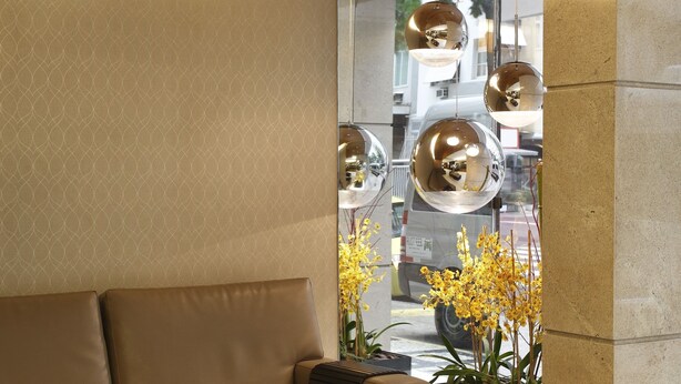 A modern interior with a sofa, a brown ottoman, and a potted plant with yellow flowers. - Copa Sul Hotel (Rio de Janeiro)