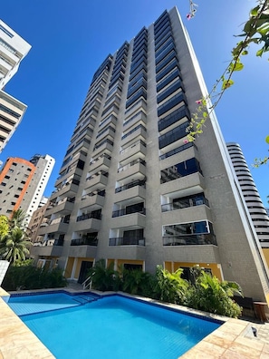 A high-rise building with a swimming pool in the foreground.