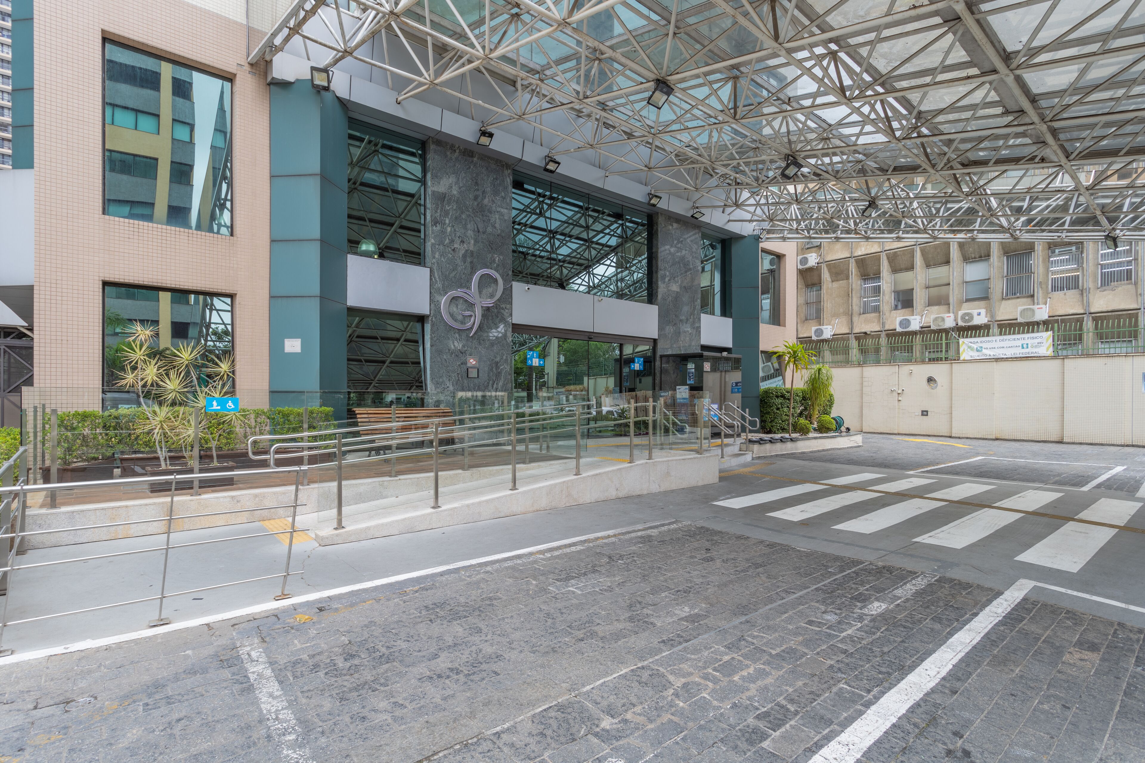 A modern building with a glass facade, a metal roof structure, and a pedestrian crossing.