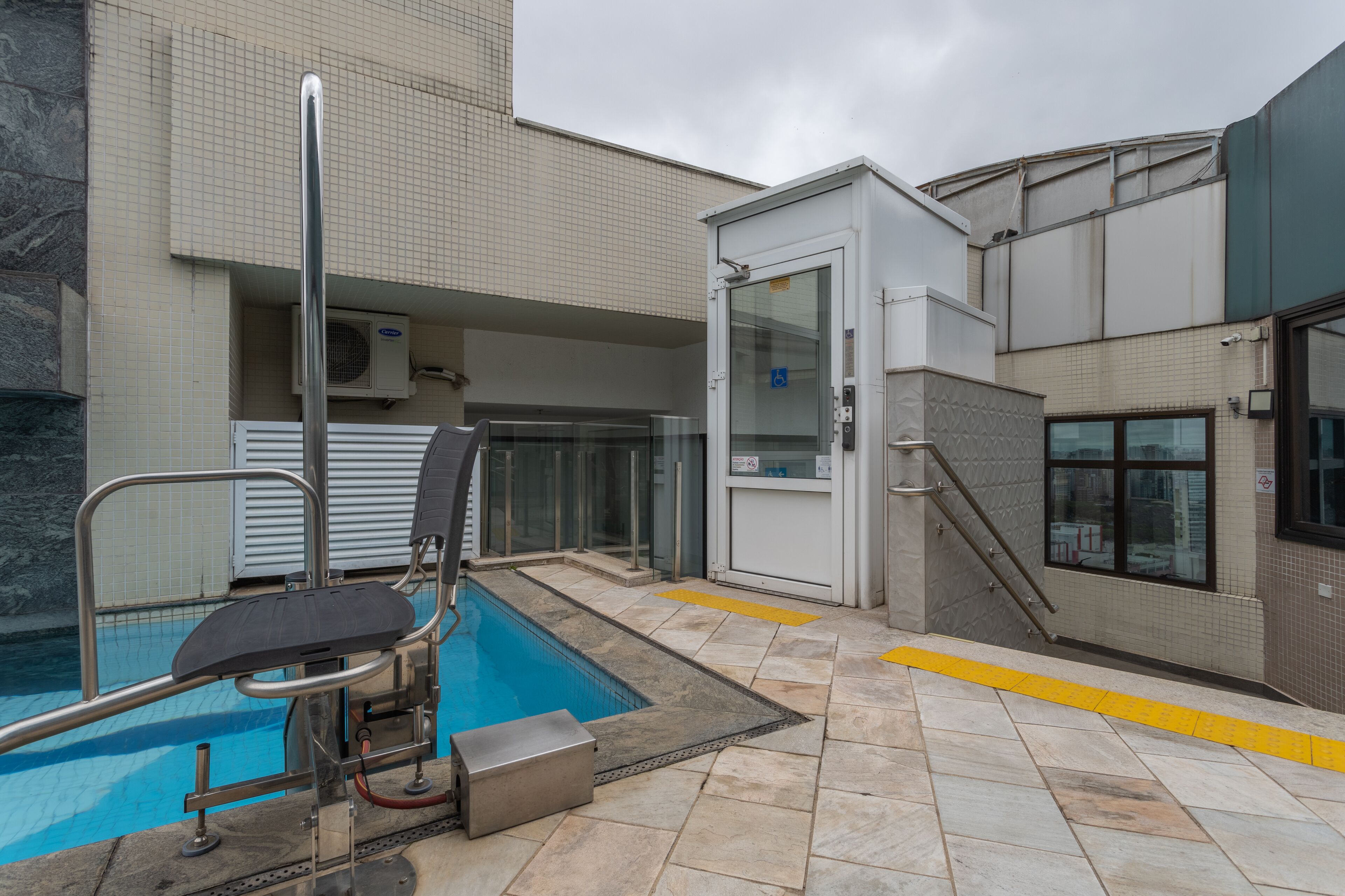 Un espace piscine comprenant un plongeoir, un vestiaire et un escalier menant à un niveau supérieur.
