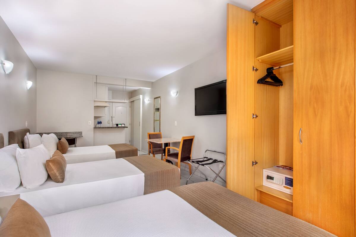 A hotel room with two beds, a desk, a chair, a TV, and a wardrobe.