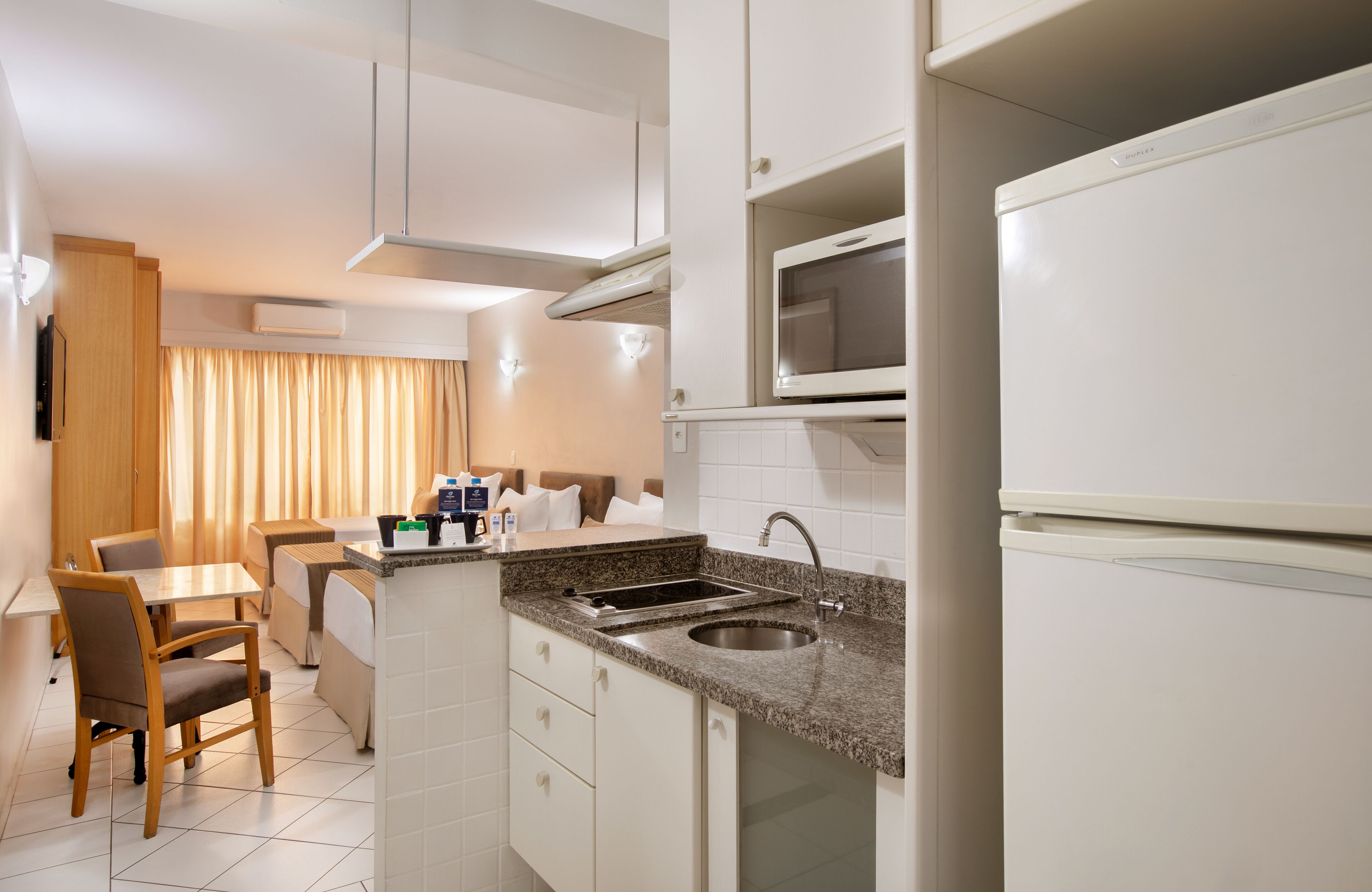 A compact kitchen with a sink, microwave, and a dining area with a table and chairs.