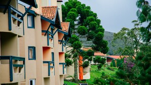 A multi-story building with balconies, a pathway, and surrounding greenery. - Plaza Inn Week Inn (Campos do Jordão)