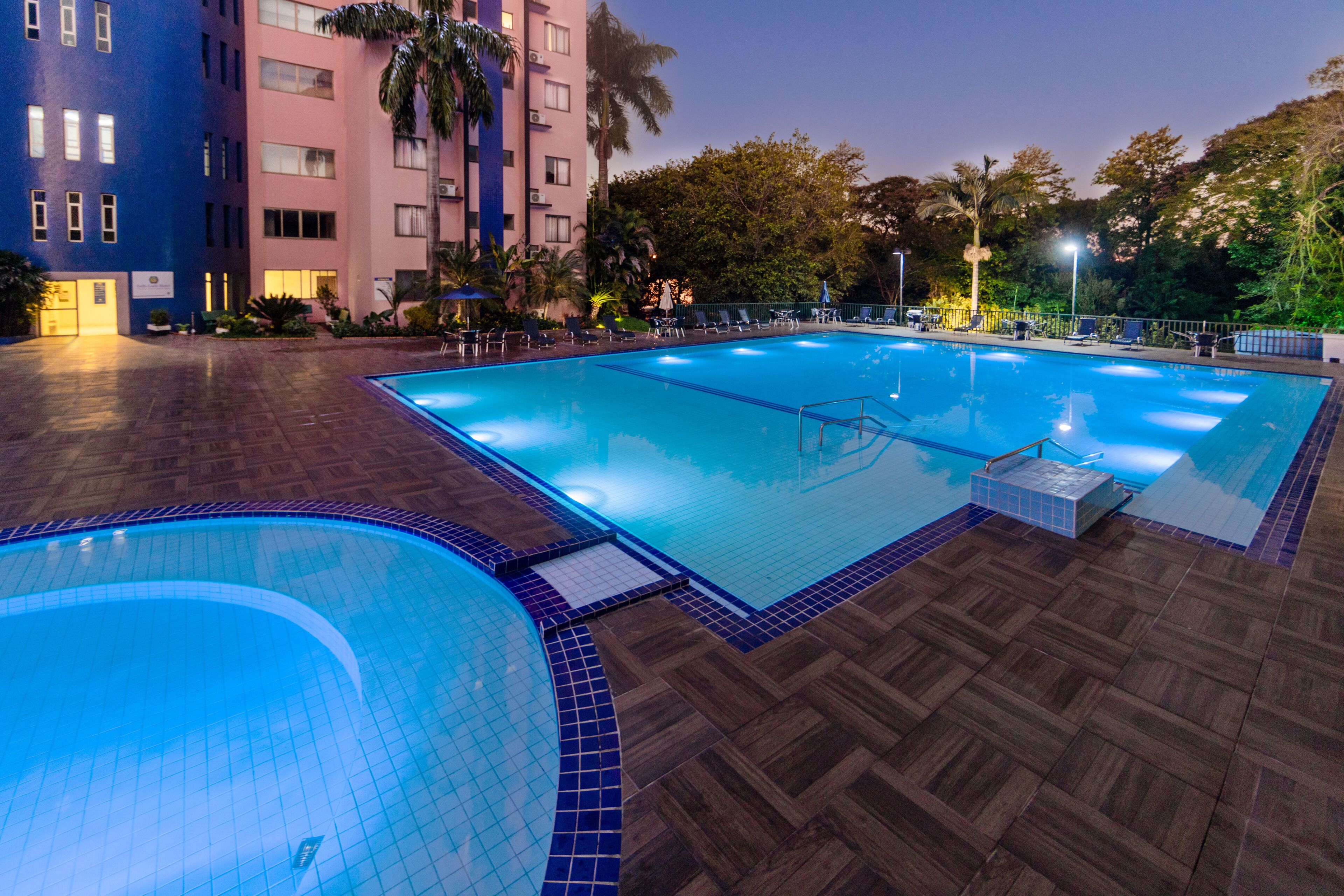 Una piscina con bordes de azulejos y una cubierta de madera alrededor.