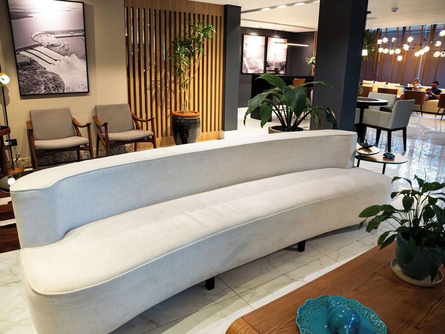A modern hotel lobby with a curved sofa, seating area, and potted plants.