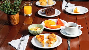 Una mesa de comedor con platos de comida, un vaso de jugo de naranja, una taza de café y una planta.