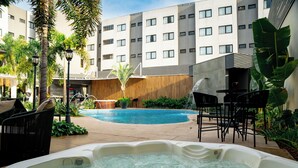 Ein Hotelinnenhof mit Swimmingpool, Sitzgelegenheiten im Freien und einer Whirlpool.