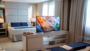 Ein Hotelzimmer mit Bett, Fernseher, kleinem Schreibtisch und einer Sitzecke.