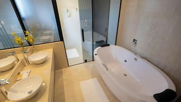 A modern bathroom with a large bathtub, two sinks, and a glass shower enclosure.