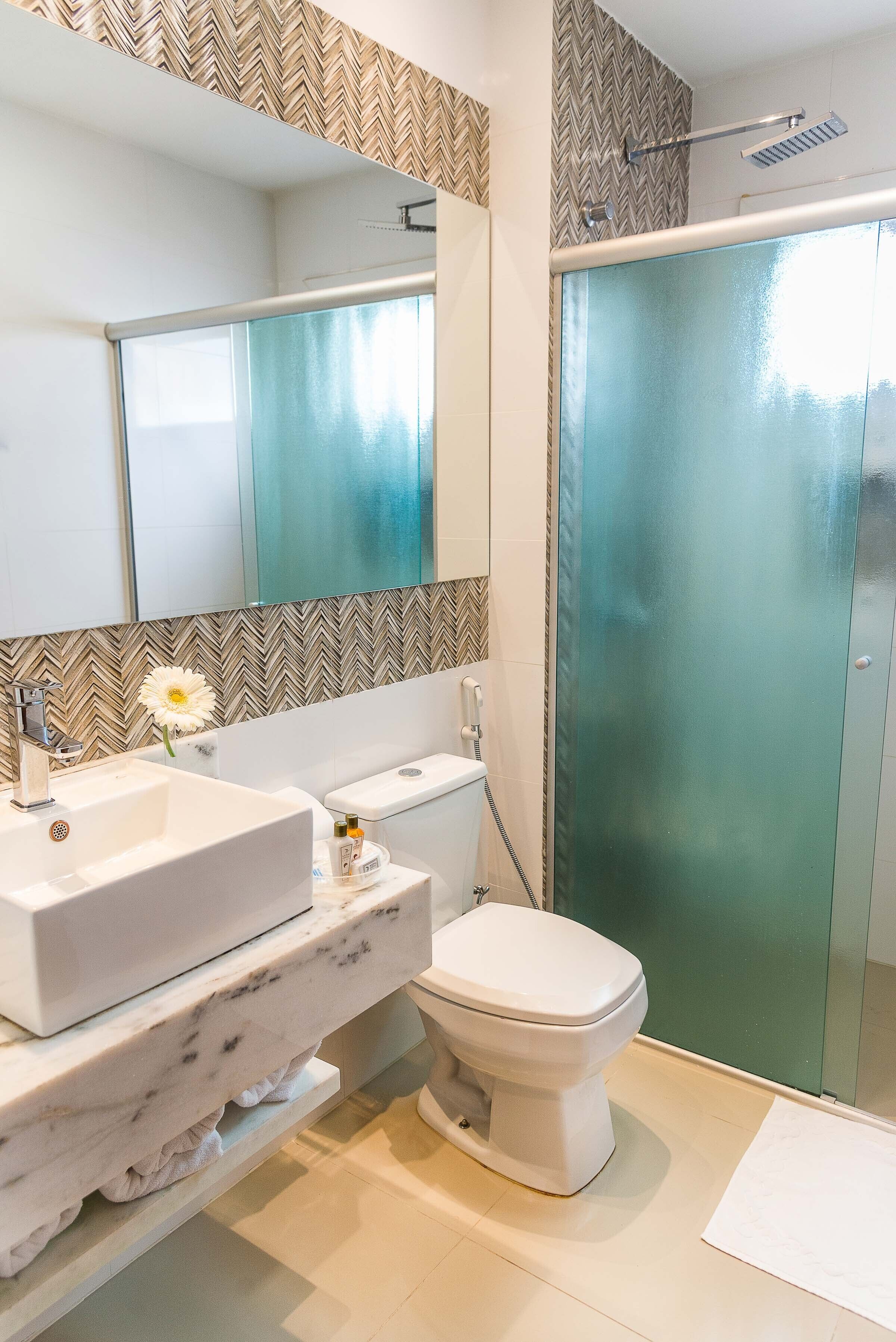 Un baño con lavamanos blanco, inodoro y cabina de ducha de vidrio.