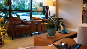 Eine moderne Lobby mit Ledersofas, einem Holzbüro und einem großen Fenster mit Blick ins Freie.