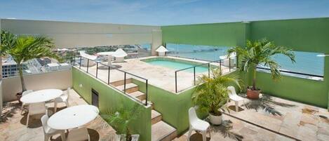 Una piscina al aire libre, sillones reclinables de piscina