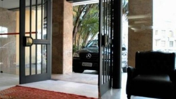 A modern hotel entrance with a glass door, a red carpet, and a parked car outside. - Duque Center Hotel (Porto Alegre)