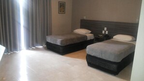 A hotel room with two beds, a nightstand, a lamp, and a painting on the wall. - Duque Center Hotel (Porto Alegre)