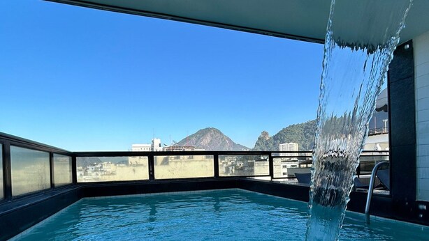 Una piscina con agua cristalina y una montaña al fondo.