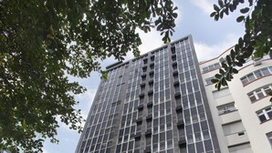 Un edificio alto con fachada de vidrio y varias banderas. El edificio tiene un letrero que dice "REAL PALACE HOTEL".