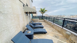 Terraza en la azotea con sillones de descanso y una palmera.