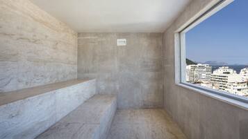 A small, modern room with a concrete wall, a window, and a view of buildings.