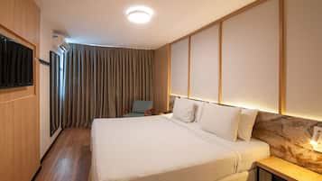 Una habitación de hotel con una cama, una silla, un televisor y aire acondicionado instalado en la pared.