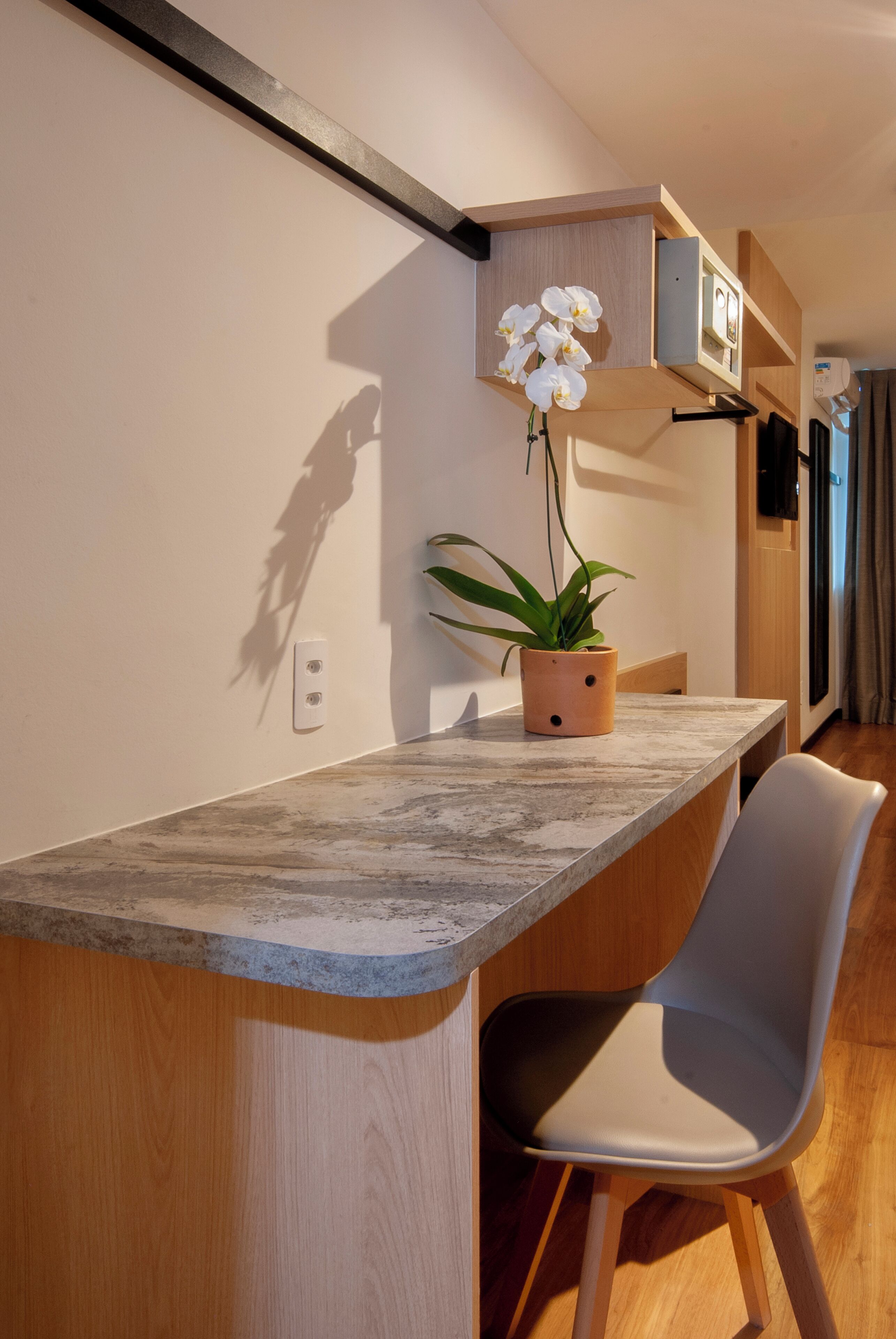 Una cocina moderna con encimera de mármol, una orquídea en maceta y una silla de madera.