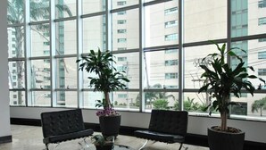A modern waiting area with black leather chairs, a glass coffee table, and potted plants. - Piemonte Hotel (Nova Lima)