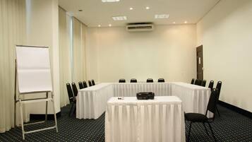 Una sala conferenze con un lungo tavolo, sedie, una lavagna e un condizionatore.