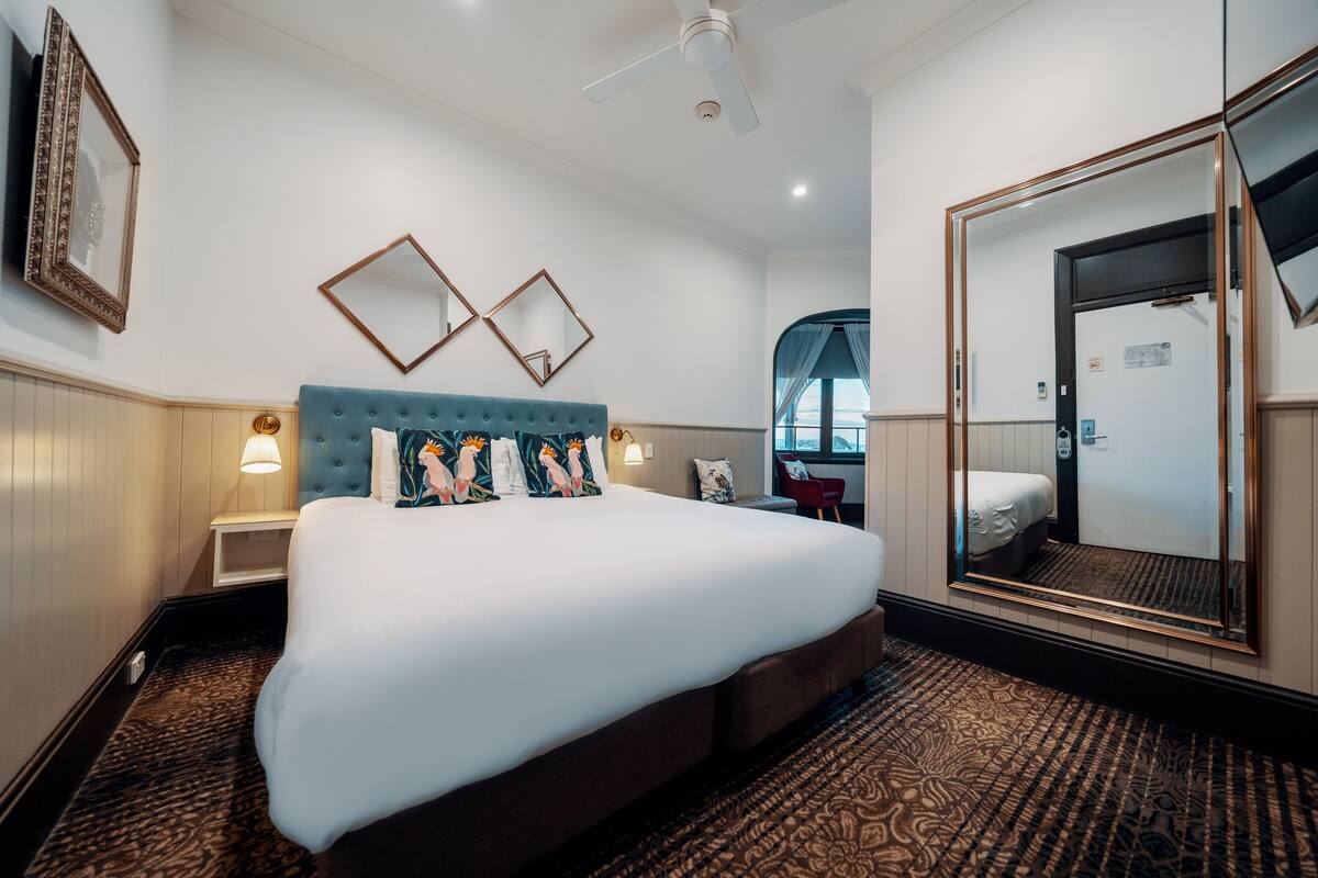 Ein Hotelzimmer mit einem großen Bett, einem Spiegel und einem Fenster.