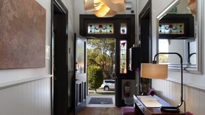 A hallway with a wooden desk, a chair, a lamp, and a door leading outside. - Cremorne Point Manor (Cremorne Point)