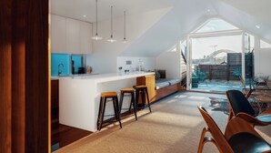 A modern kitchen with a central island, bar stools, and a view of a bridge through large windows. - Cremorne Point Manor (Cremorne Point)