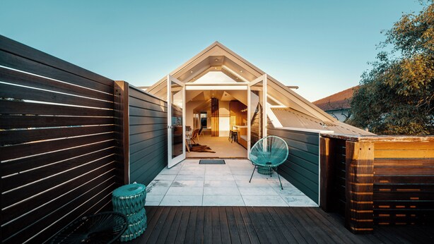 A modern house with a sloped roof, a covered patio, and a visible interior with a dining area. - Cremorne Point Manor (Cremorne Point)