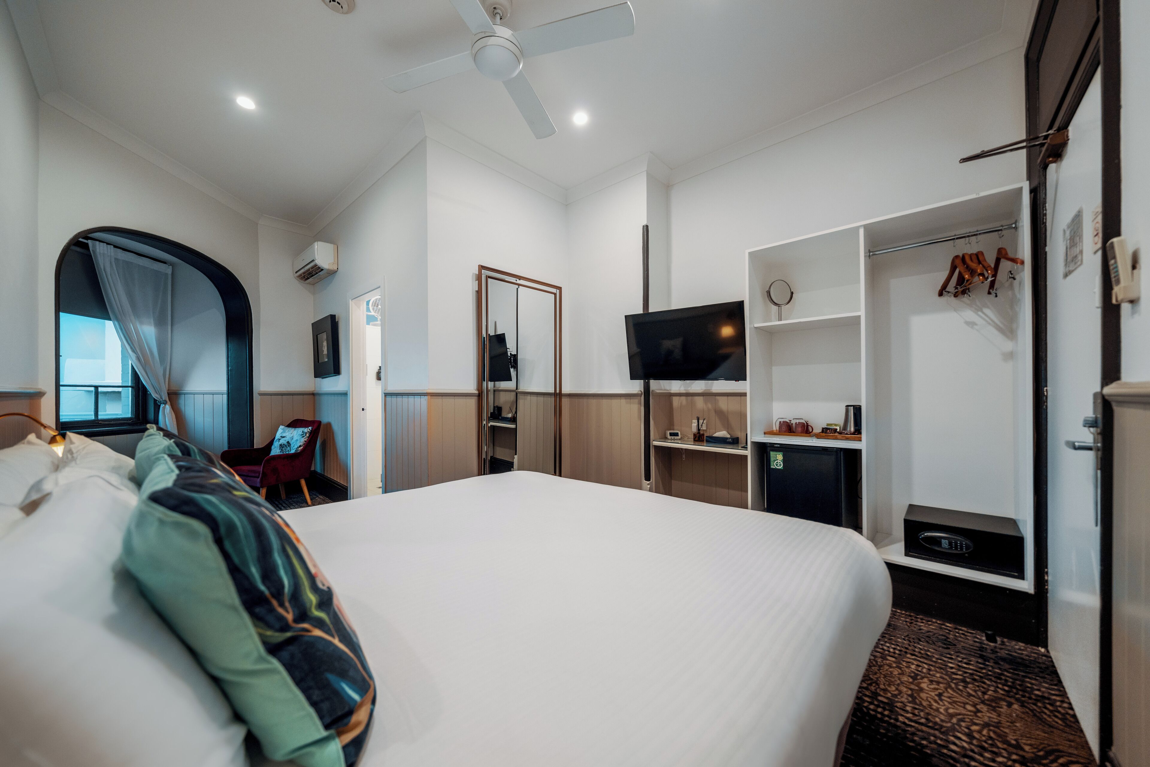 Una habitación de hotel con una cama grande, televisión, armario y escritorio con silla.