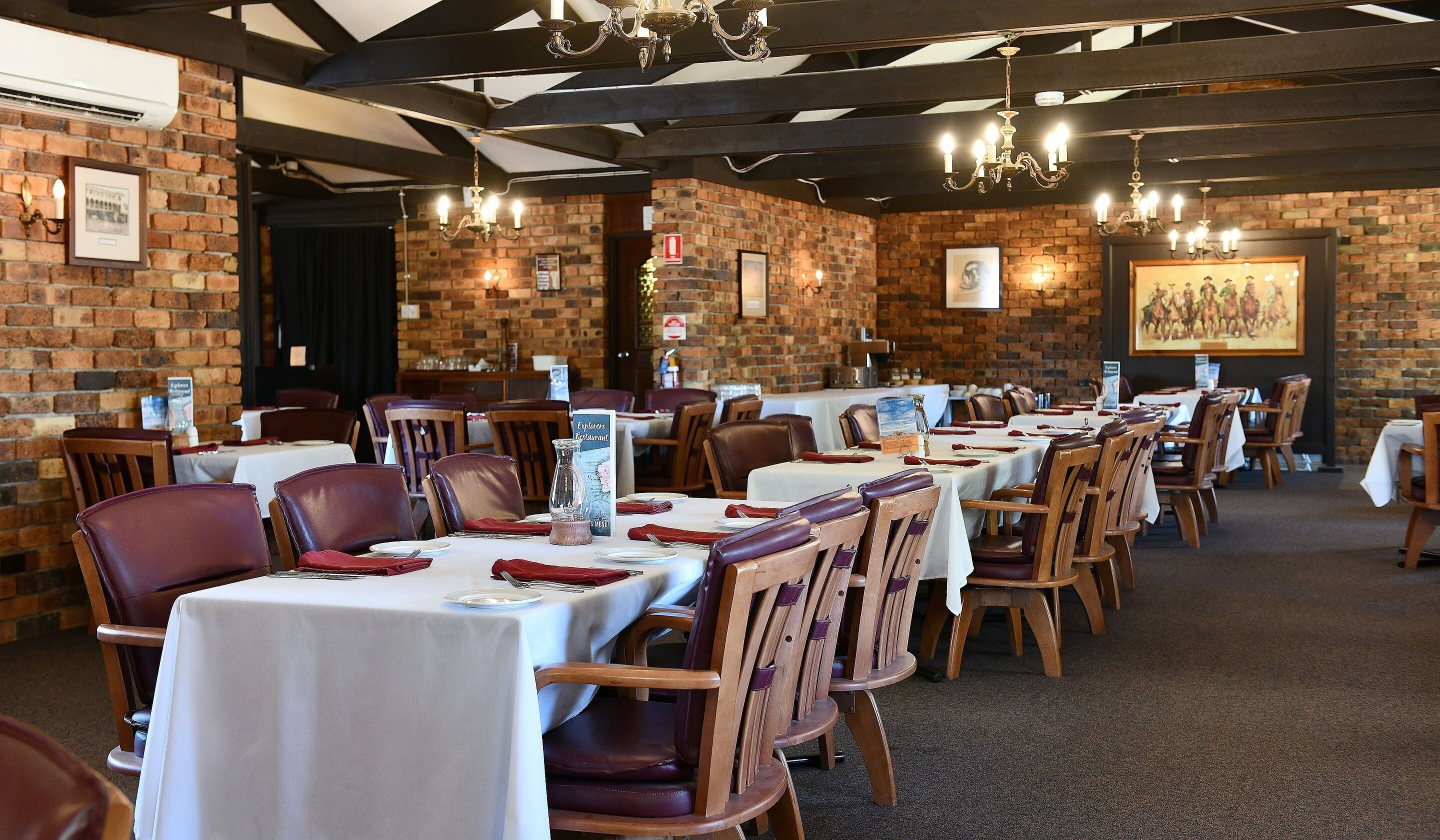 Un restaurant aux murs de briques, aux tables en bois et aux chaises en cuir.