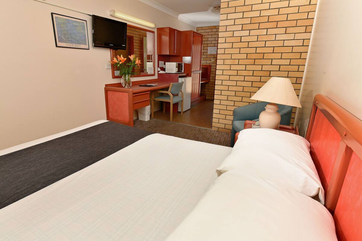 Una habitación de hotel con una cama, un escritorio, una silla, una lámpara y un televisor.