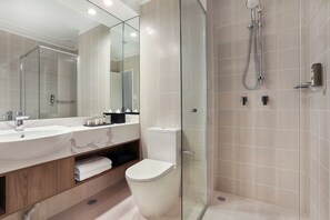 A modern bathroom with a glass-enclosed shower, a large mirror, and a vanity with two sinks.