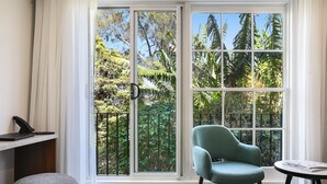 A room with a large window, a green chair, a small table, and a telephone on a desk. - Killara Hotel & Suites (Killara)
