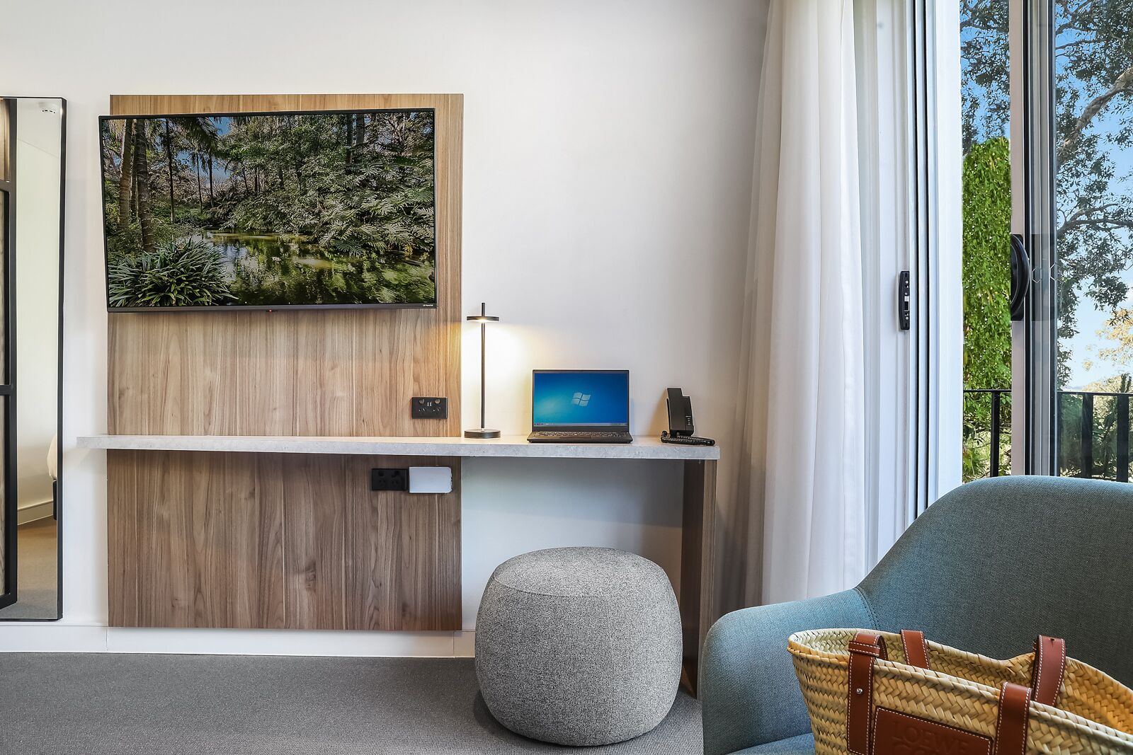 A modern room with a desk, laptop, and a large window.