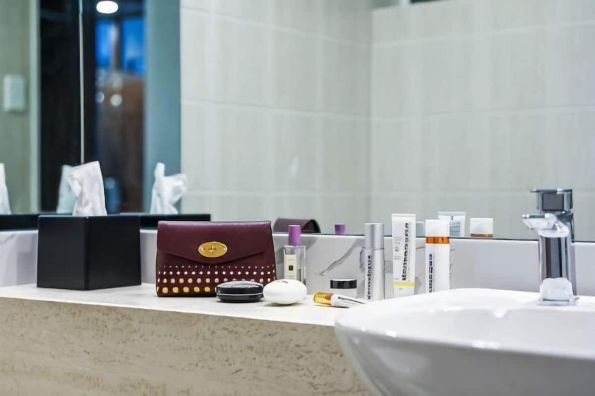 Ein Badezimmer-Waschtisch mit Pflegeprodukten, einem Spiegel und einem Waschbecken.