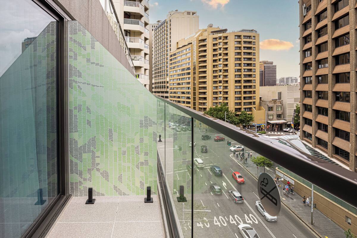Un edificio moderno de gran altura con fachada de vidrio que refleja el cielo y edificios circundantes.