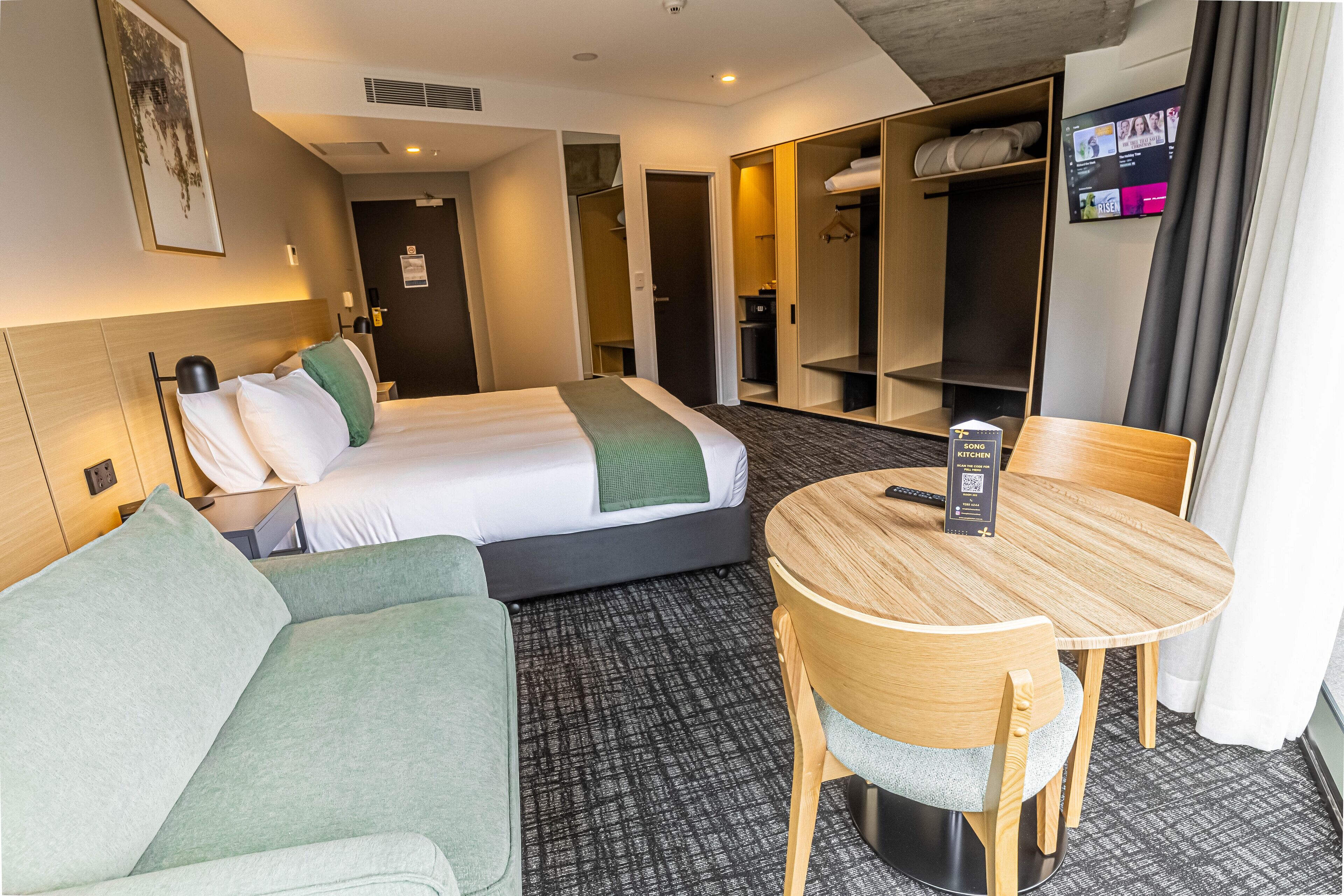 Una habitación de hotel con una cama, un sofá, una mesa de comedor y un televisor.