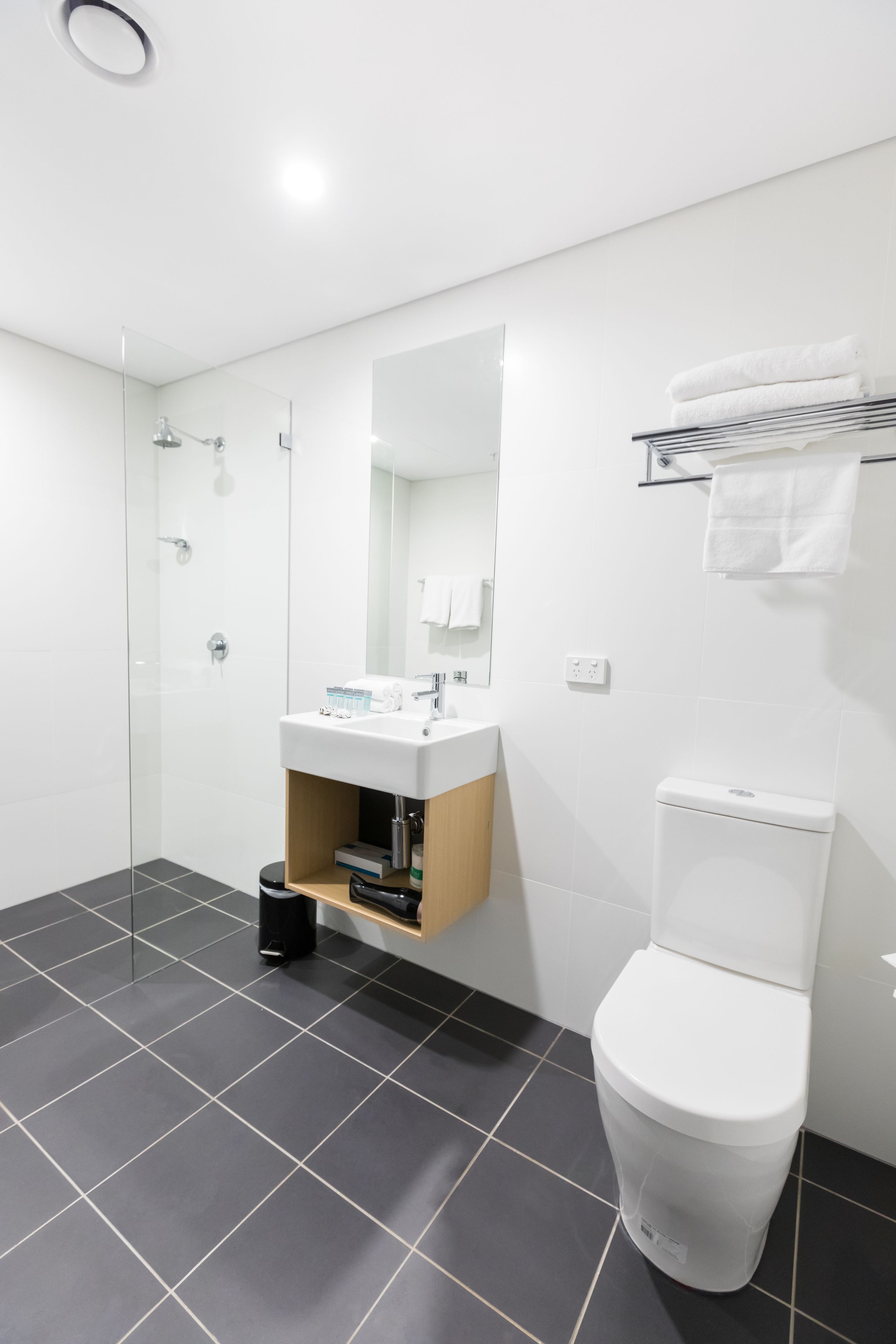 Uma casa de banho moderna com cabine de duche em vidro, lavatório branco com espelho e sanita.