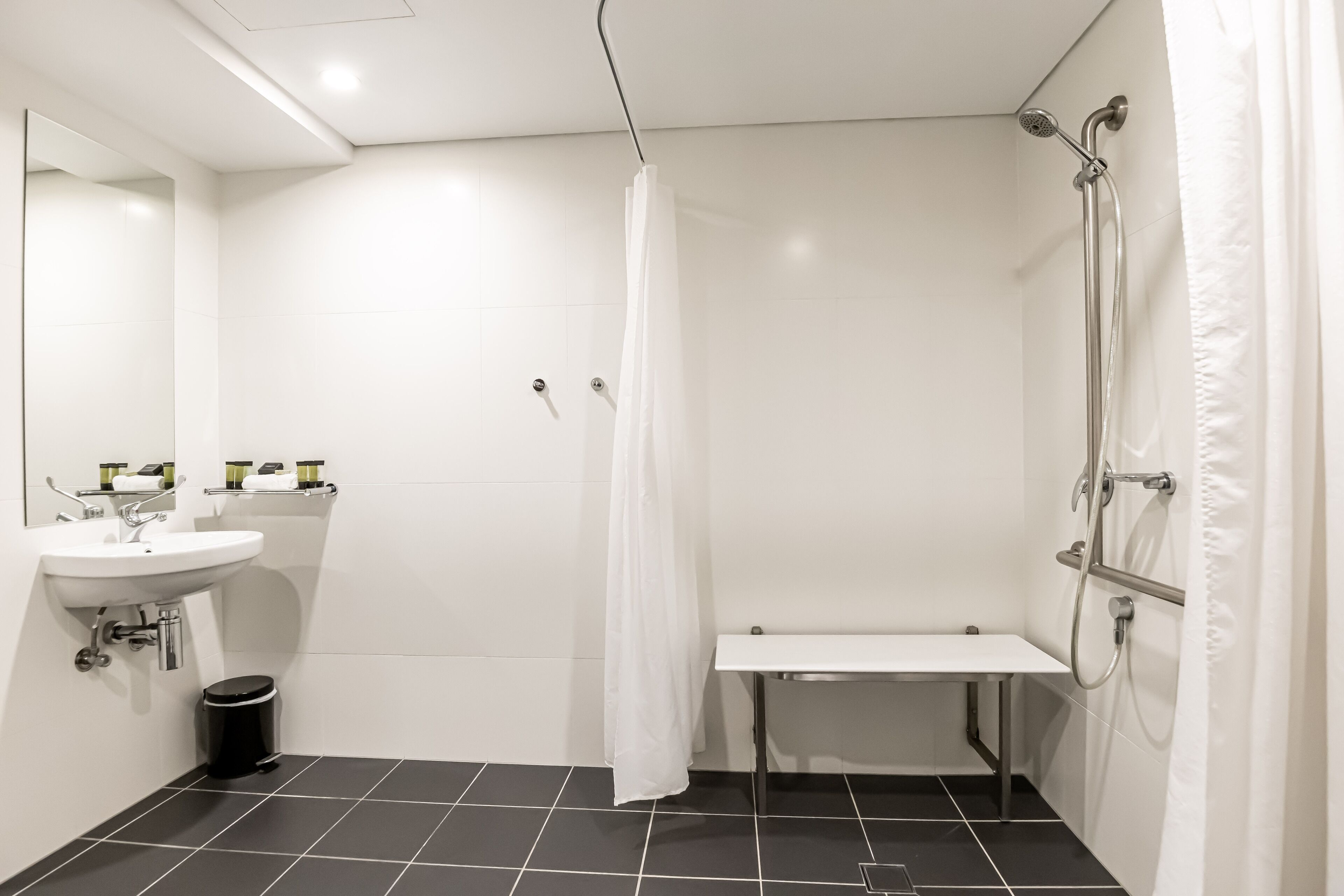 Un baño moderno con lavamanos blanco, espejo y zona de ducha.