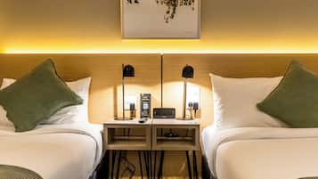 A hotel room with two beds, a small table with a digital clock, a sign for a Philips device, and a wall-mounted artwork.