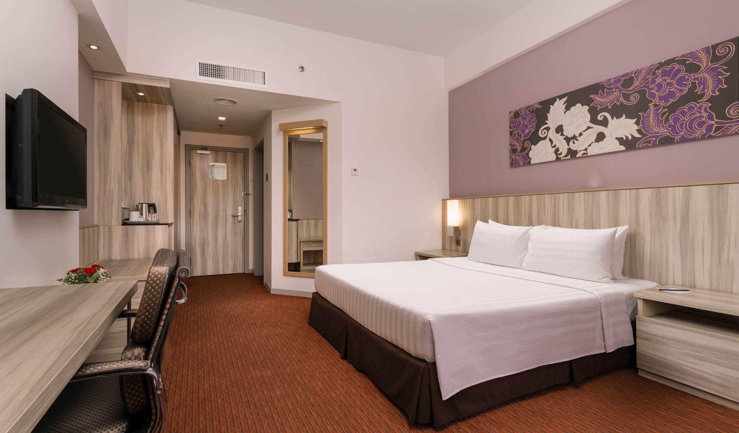 Una habitación de hotel con cama, mesita de noche, televisor, escritorio y silla.