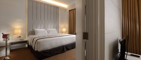 Una habitación de hotel con una cama grande, mesitas de noche, un televisor y un diseño moderno.
