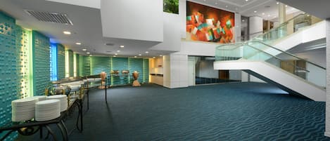 Un hall d’entrée spacieux avec un plafond haut, un escalier et une grande fresque murale.