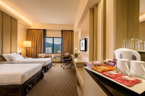 A hotel room with two beds, a desk with coffee cups and snacks, a chair, and a view of the city. - Sunway Hotel Georgetown Penang (George Town)