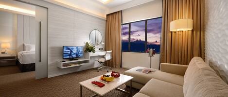 Una habitación de hotel moderna con cama, televisor, escritorio, sofá y un amplio ventanal con vistas.
