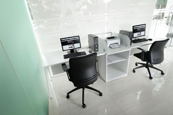 Un bureau moderne équipé de deux postes de travail, chacun comprenant un ordinateur, un clavier et une souris. On y trouve également deux chaises de bureau et une imprimante sur les bureaux.